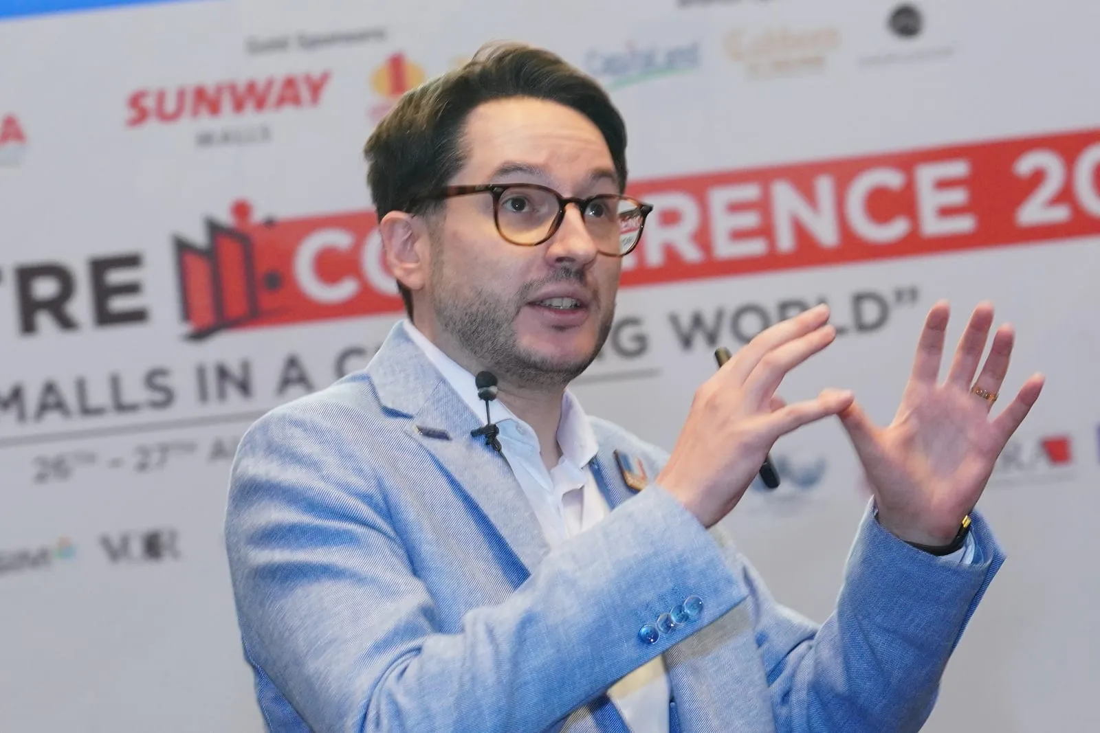Matteo Borghi speaking on stage at the Malaysia Mall Association Conference 2025, gesturing with both hands